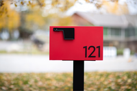 An Adoorn Red Red Locking Post Mount mailbox installed curbside in a suburban residential context, the AD 'Best Overall' pick