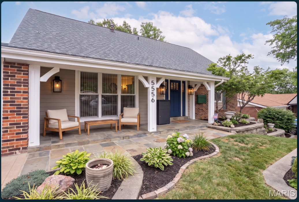 After: the covered porch with wood seating, warm lanterns, a green mailbox, package box, stone walkway and refreshed garden beds.