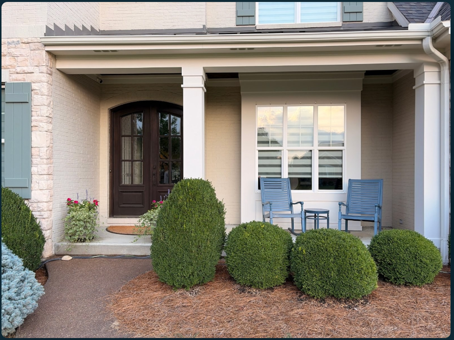 Before: a brick porch with a dark front door, blue rocking chairs, large boxwoods and a concrete path.