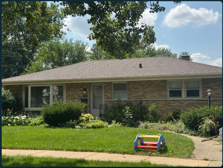 Before: a brick ranch home with dense shrubs around a small entry, a curved concrete path and a lawn with a colorful play structure.