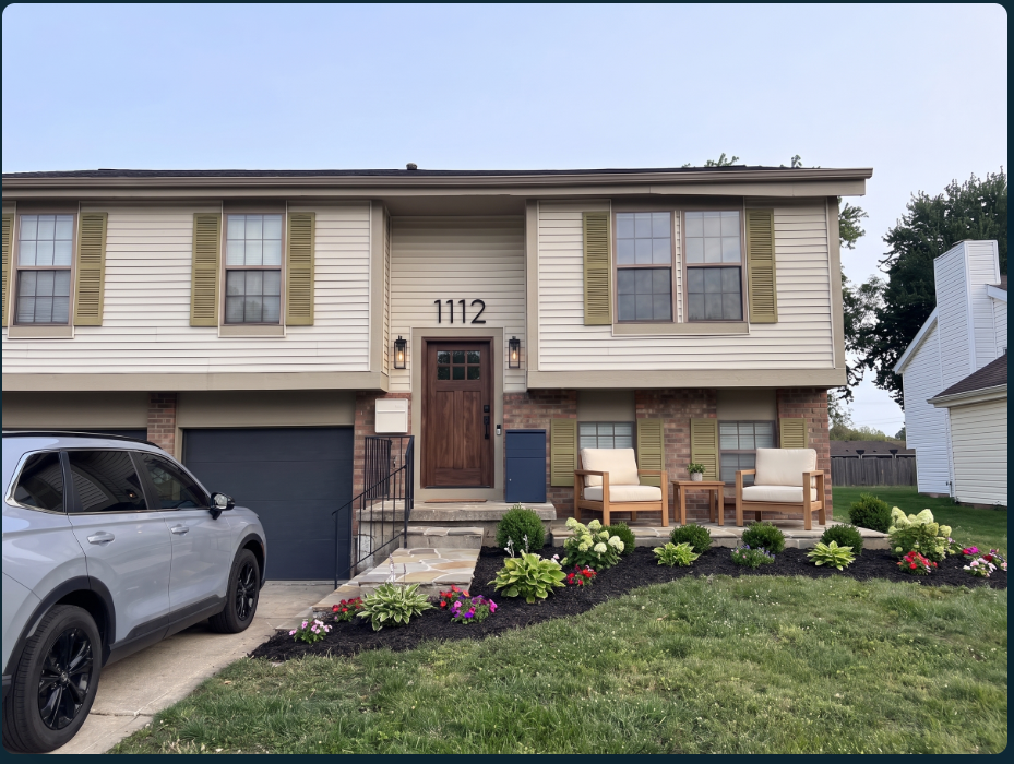 After: the home with a wood front door, white mailbox, navy package box and garage door, porch seating and refreshed planting beds.